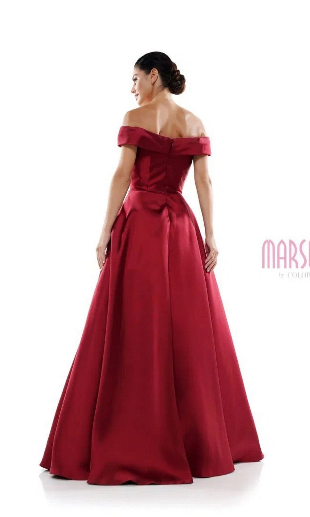 A woman stands facing away from the camera in the Marsoni MV1008, a long formal off-the-shoulder dress. The deep red satin gown flows gracefully to the floor against a white background.